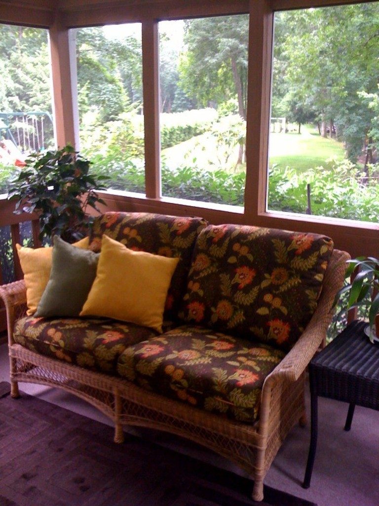 Sunroom with a patterned sofa, cushions and garden views
